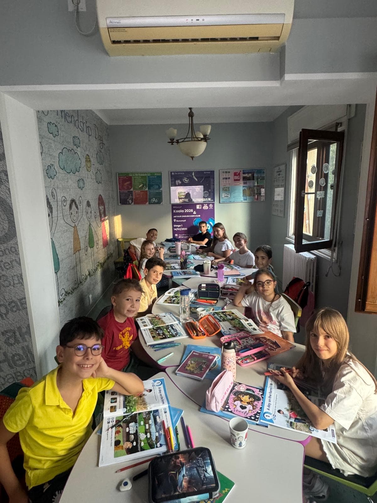 Elevi Arthur English Kids Club la o lecție, lucrând la masă cu manualele deschise